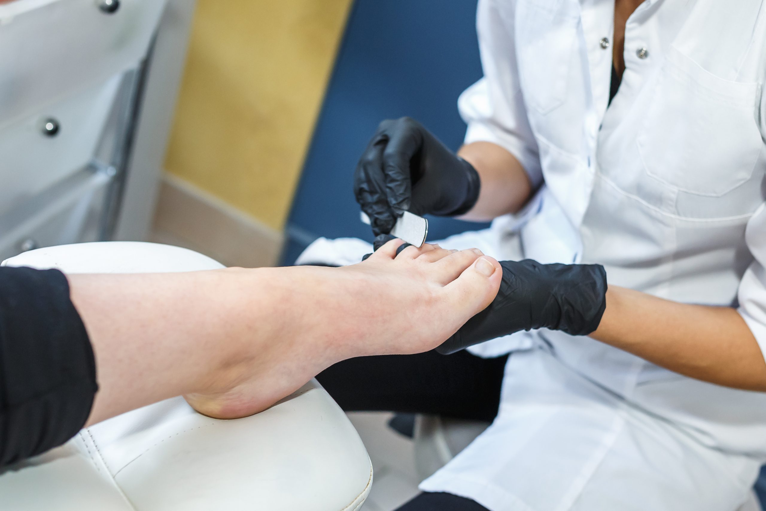 the master in black gloves in the salon makes manicure pedicure to the client
